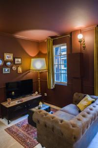 een woonkamer met een bank en een televisie bij Le Garrison - l'univers des Peaky Blinders à Bergerac in Bergerac