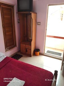 Un dormitorio con una cama y un televisor y una ventana. en Hotel Srusti Residency, en Mysore