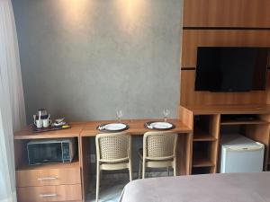 a room with a table with two chairs and a microwave at Flat Comfort Taguatinga - Cama King - Sauna, academia e Piscina - Propriedade Particular 508 in Brasilia