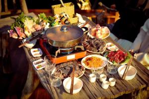 a table with food and a pot on top of it at Háng Đồng Ecolodge in Bắc Yên