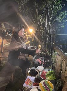 a woman is cooking food on a grill at Háng Đồng Ecolodge in Bắc Yên +48 photos