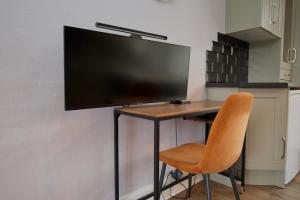 a desk with a television on a wall with a chair at Whitley House - Stylish 3 Bedroom Home near Coventry City Centre in Coventry