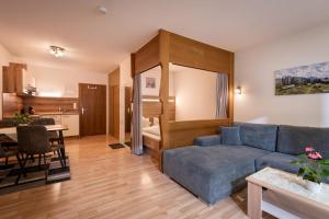 a living room with a blue couch and a kitchen at Appartementhaus Montana KG in Walchsee