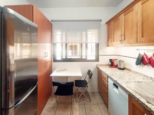 a kitchen with a refrigerator and a counter with chairs at Los Azahares Apartment in Costa Del Silencio