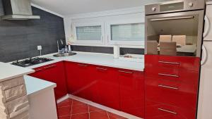 een rode keuken met witte toonbanken en rode kasten bij Apartman Kovačić in Kutina +2 foto's