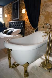 een wit bad in een kamer met een bed bij Le Garrison - l'univers des Peaky Blinders à Bergerac in Bergerac +22 foto's