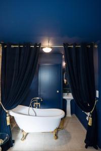 een blauwe badkamer met een wit bad en een blauwe muur bij Le Garrison - l'univers des Peaky Blinders à Bergerac in Bergerac