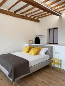 a white bedroom with a large bed with yellow pillows at Sara Home in Guarene