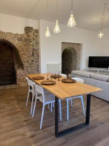 a dining room with a wooden table and white chairs at Sara Home in Guarene