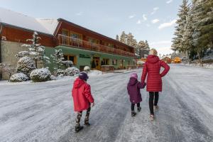 Una mujer y dos niños caminan por una calle cubierta de nieve. en Hotel Polovnik, en Demänovská Dolina