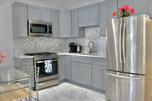 a kitchen with white cabinets and a stainless steel refrigerator at 2-Bedroom Apartment 15 Minutes From Manhattan in LIC Astoria Queens  +12 photos