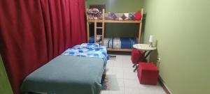 La Bellota Surf House Huanchaco في هوانتشاكو: غرفة نوم صغيرة بسرير وستارة حمراء +7 صور