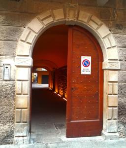 une arche avec une porte brune portant une pancarte. dans l'établissement BGY Maison del Borgo 1, à Bergame