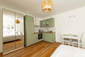 une cuisine avec des armoires vertes et une table dans une pièce dans l'établissement BGY Maison del Borgo 1, à Bergame