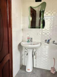 a bathroom with a white sink and a mirror at Kinigi Holiday Home in Kinigi