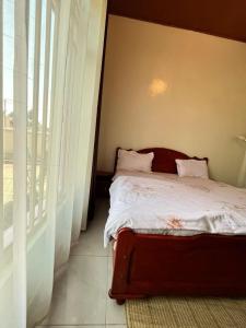 a bedroom with a bed with white sheets and a window at Kinigi Holiday Home in Kinigi
