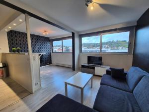 ein Wohnzimmer mit einem blauen Sofa und einem Tisch in der Unterkunft Le Berthelot #Parking in Clermont-Ferrand