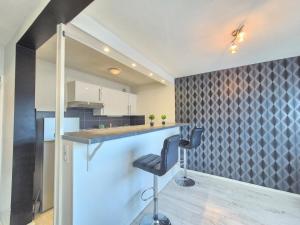 eine Küche mit einer Bar mit zwei Stühlen an einer Theke in der Unterkunft Le Berthelot #Parking in Clermont-Ferrand