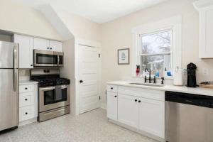 a kitchen with white cabinets and a stainless steel refrigerator at Sweet Retreat 3 Mins to Notre Dame Eddy St Commons and Memorial Hospital in South Bend +21 photos
