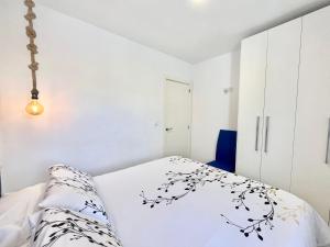 a white bedroom with a bed and a white wall at Apartamento Caravaca in Santa Pola