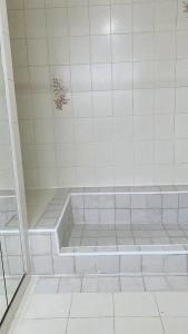 a bathroom with a shower with white tiles at Gran Via Hostel in Punta Arenas