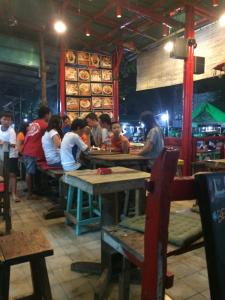 un grupo de personas sentadas en mesas en un restaurante en Ombak Homestay, en Gili Trawangan