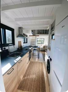 Una cocina con gabinetes blancos y una encimera negra. en Tiny House, en Pereiro