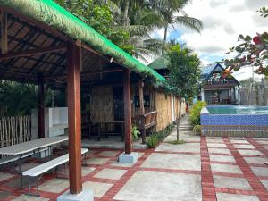 a resort with a pool and a table and benches at Beachfront Native house with pool in Nasugbu