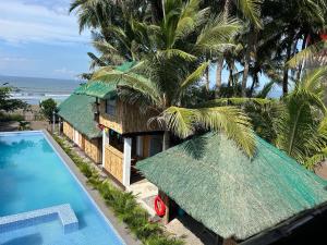 a house with a grass roof and a swimming pool at Beachfront Native house with pool in Nasugbu