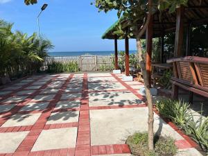 a patio with a table and benches and the ocean at Beachfront Native house with pool in Nasugbu +6 photos