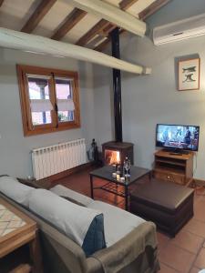 a living room with a couch and a tv at La Herrera lll in San Esteban de la Sierra