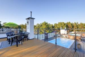 a balcony with a table and chairs and a swimming pool at Poddąbek Comfort I Apartamenty z tarasem na dachu, ogródkiem, basenem zewnętrznym i wewnętrznym, salą zabaw i animacjami in Poddąbie