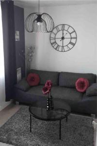 a living room with a couch and a clock on the wall at Agréable appartement in Bobigny