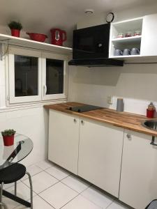 a kitchen with white cabinets and a wooden counter top at Agréable appartement in Bobigny
