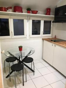 a kitchen with a glass table and some chairs at Agréable appartement in Bobigny