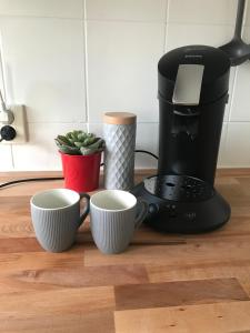 a coffee maker and two cups on a counter at Agréable appartement in Bobigny +6 photos