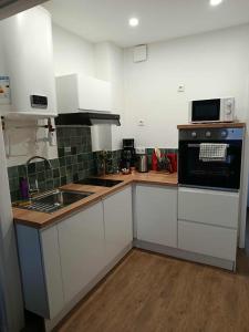 a kitchen with white cabinets and a black stove top oven at Secteur digue Dunkerque, Escale a Malo, Aquae Mare in Dunkerque