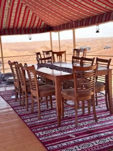 a wooden table and chairs under a tent at Desert Vibes Camp in Badīyah +38 photos