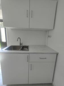 a white kitchen with a sink and white cabinets at Alma Atlântica - Pure Nature & Beach in Praia do Almoxarife