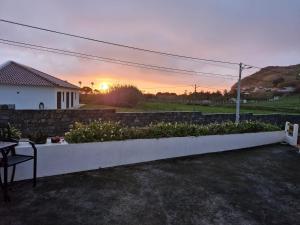 a backyard with a retaining wall and a table and a sunset at Alma Atlântica - Pure Nature & Beach in Praia do Almoxarife