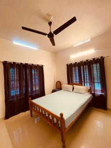 Un dormitorio con una cama con ventilador de techo. en villa mud apples, en Varkala