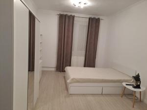 a small white bedroom with a bed and a table at Studio One in Făgăraş +2 photos
