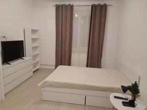 a white bedroom with a bed and a tv at Studio One in Făgăraş