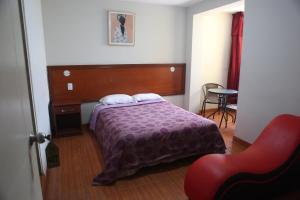 een slaapkamer met een bed en een rode stoel bij Hostal Real in Lima