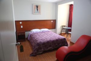 een slaapkamer met een bed en een rode stoel bij Hostal Real in Lima