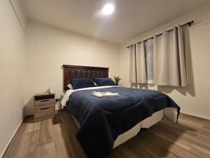 a bedroom with a large bed with a blue blanket at AH Residencial in Antofagasta