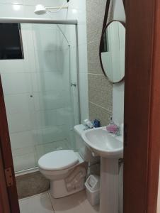 a bathroom with a toilet and a sink and a mirror at Sobrado Harmonia in Ponta Grossa