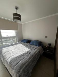 ein Schlafzimmer mit einem Bett mit blauen Kissen und einem Fenster in der Unterkunft Depto Peñuelas in Coquimbo