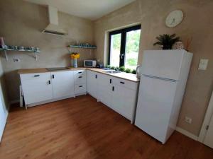 a kitchen with white cabinets and a white refrigerator at Malëna Mausz in Parchowo +7 photos
