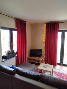 a living room with a couch and red curtains at Malëna Mausz in Parchowo